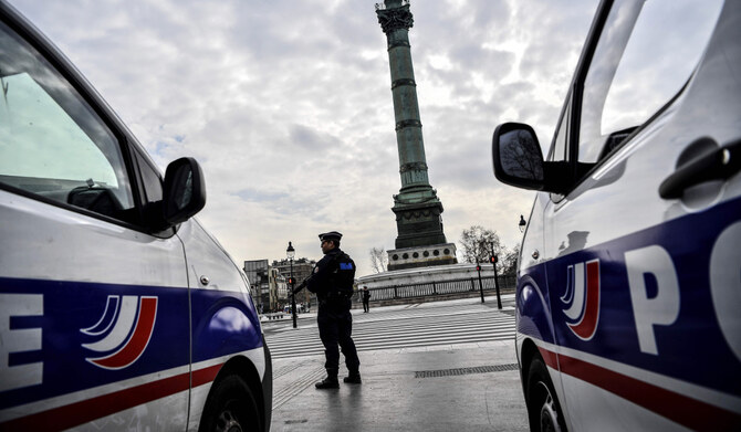 A French police officer stands by police vehicles during checks on drivers at Place de la Bastille in Paris on March 17, 2020. (AFP)