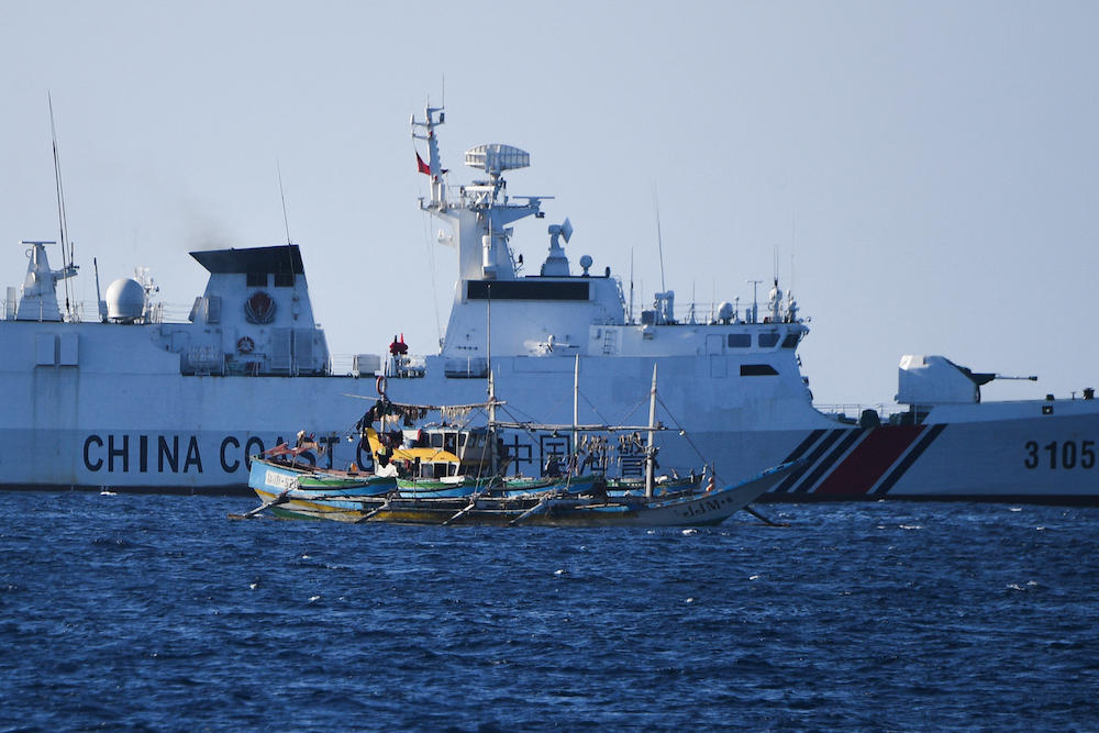 A Chinese coast guard ship sails past a Philippine fishing boat near the China-controlled Scarborough Shoal, in disputed waters of the South China Sea in this photo taken on Feb. 15, 2024. (AFP)