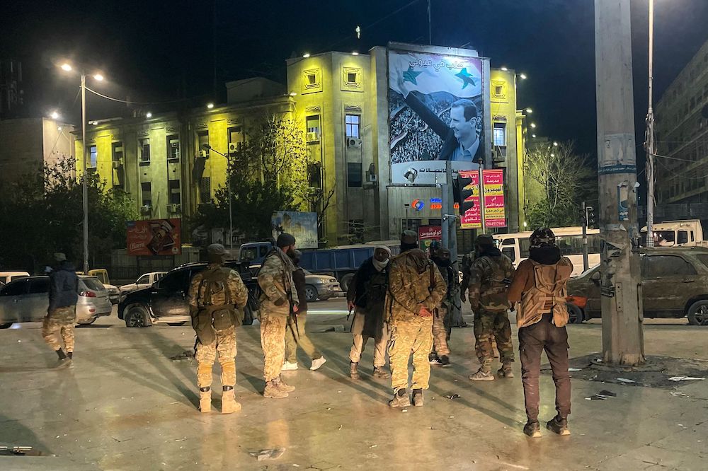 Above, militants gather in central Aleppo in front of a building bearing a large picture of Syria’s President Bashar Assad early on Nov. 30, 2024. (AFP)