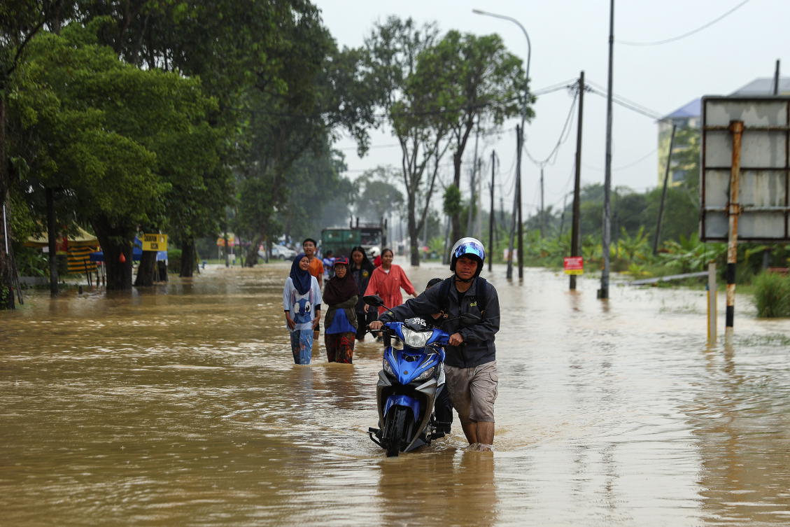 A man pushes his motorcycle as he wades through a flooded area in Klang, state of Selangor, Malaysia, 29 November 2024. According to the National Disaster Control Center (NDCC) report of the National Disaster Management Agency (NADMA), over 84,500 people have been displaced due to the floods nationwide, while four deaths have been recorded across the states of Kelantan, Terengganu and Sarawak. (EPA/FAZRY ISMAIL)