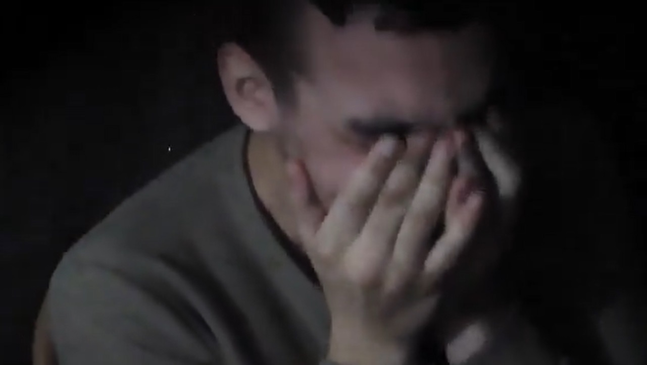 A screengrab taken from a video showing Israel hostage soldier Edan Alexander, 20, sitting in a dark space against a wall, identifying himself, addressing his family, Israeli PM Benjamin Netanyahu and Trump. (X/ @AvivaKlompas)