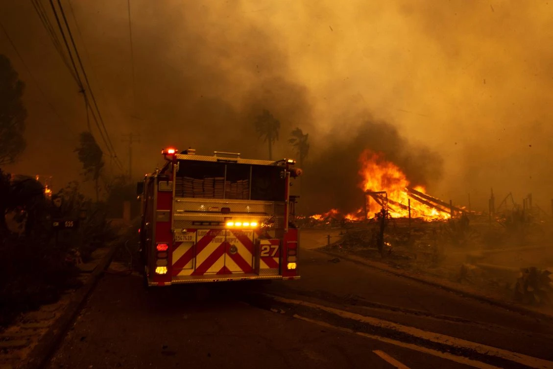 A house burns next to a firetruck as the Mountain Fire scorches acres in Camarillo Heights, Camarillo, California, on November 6, 2024. (AFP)