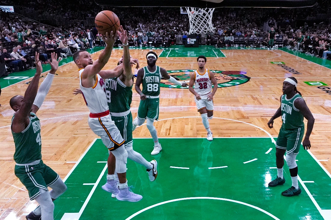 Golden State Warriors guard Stephen Curry, left, takes a shot against the Boston Celtics during the second half of an NBA basketball game Wednesday in Boston. (AP)