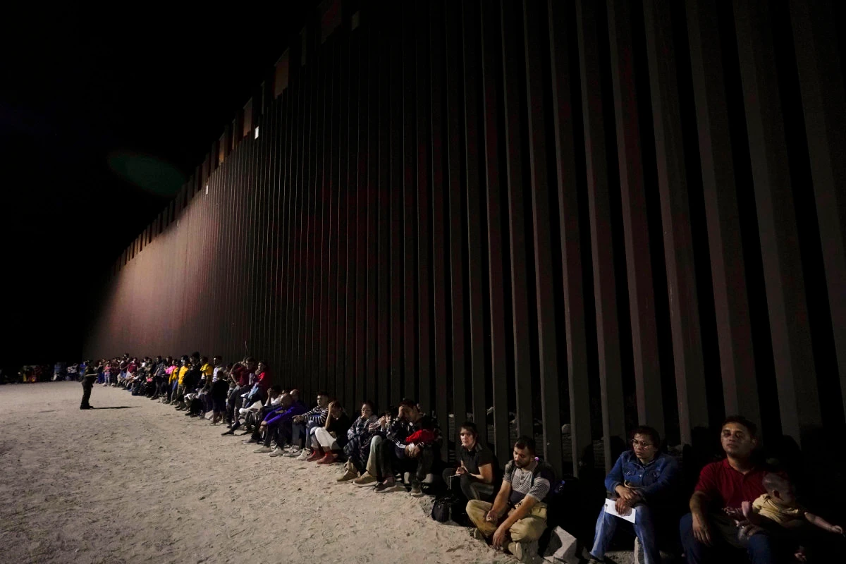 In this file photo, migrants wait to be processed after crossing into the United States near the end of a border wall near Yuma, Arizona. US president-elect Donald Trump has promised mass deportations of illegal immigrants once he sets foot at the White House. (AP)