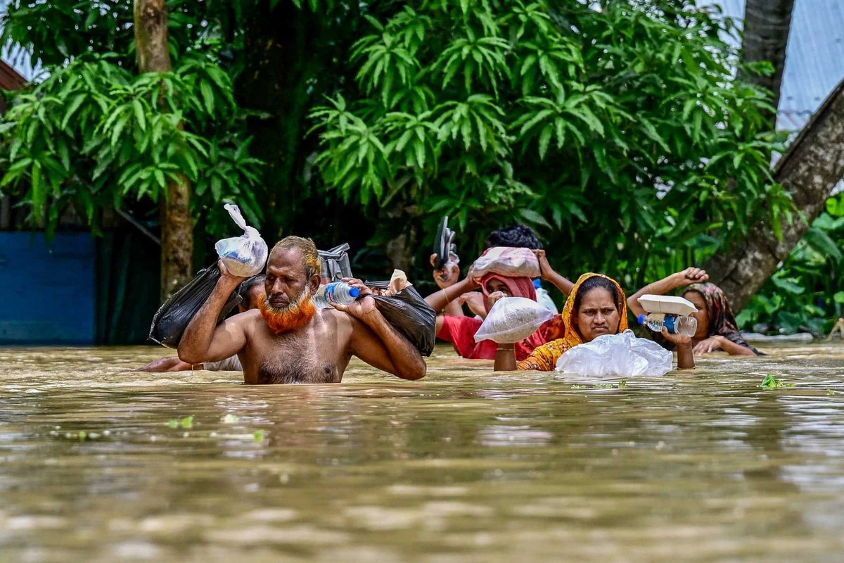 People carrying relief materials wade through flood waters in Feni, in south-eastern Bangladesh, on Aug. 24, 2024. (AFP)