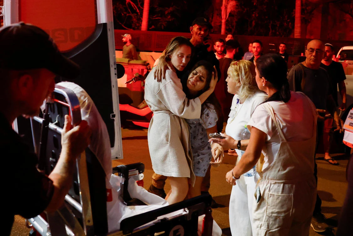 A woman is embraced and reacts near an impact site while she prepares to get into an ambulance, amid hostilities between Hezbollah and Israeli forces, in Nahariya, on Nov. 12, 2024. (Reuters)