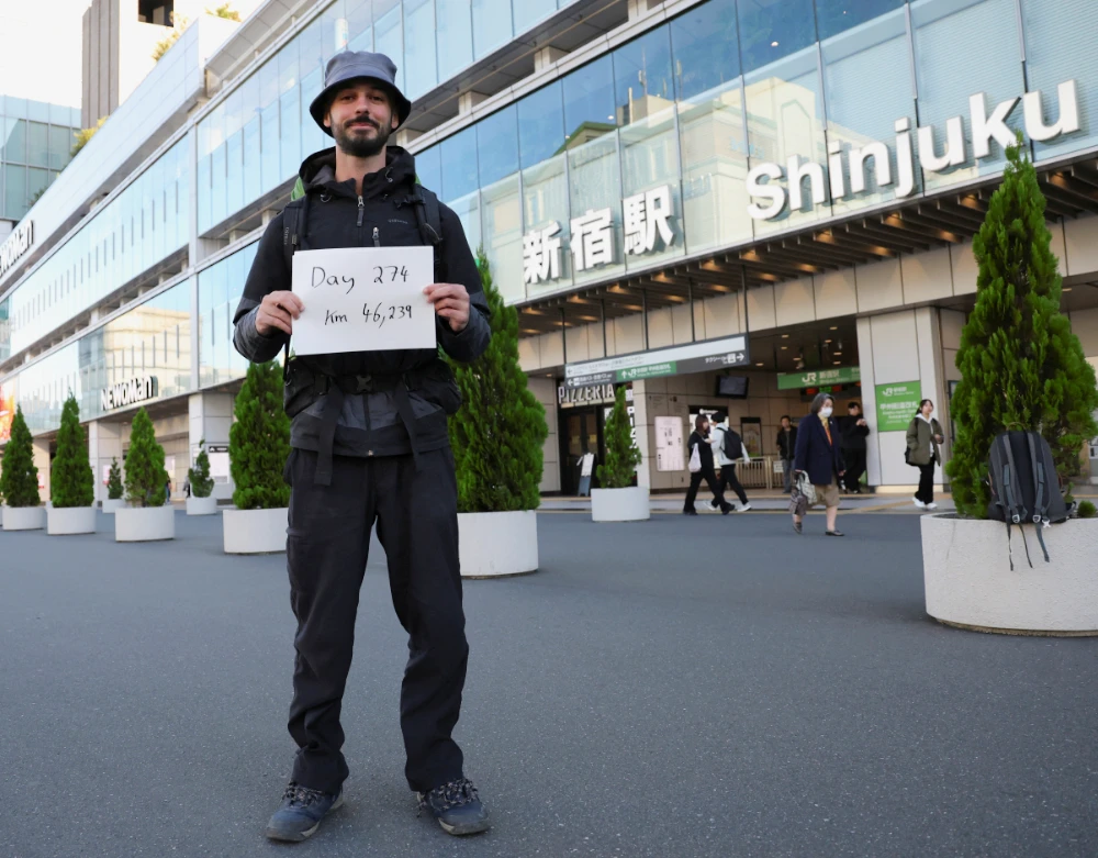 Omar Nok, a 30-year-old Egyptian who travelled from Cairo to Tokyo, holds a sign noting the days and distance he has travelled, in front of Shinjuku station in Tokyo, Japan. (Reuters)