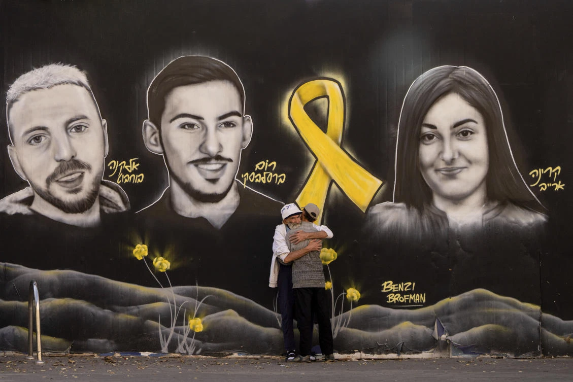 People hug next to graffiti portraits of Gaza-held hostages in Jerusalem, Nov. 22, 2024. (AP)