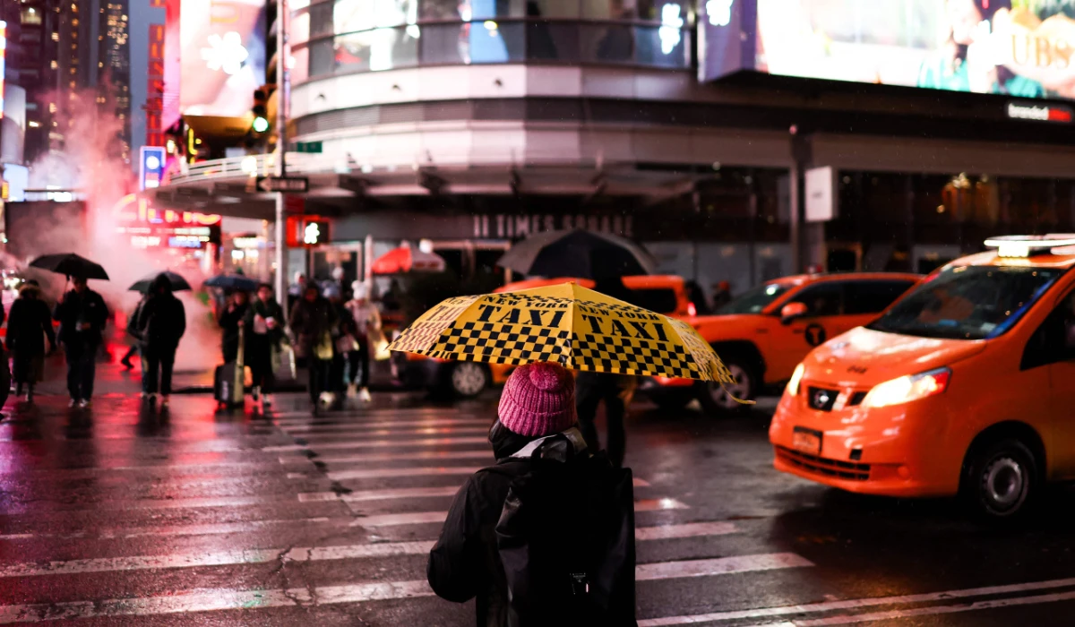 People hold umbrellas as they walk under the rain in a street of the Manhattan borough of New York City on November 22, 2024. (AFP)
