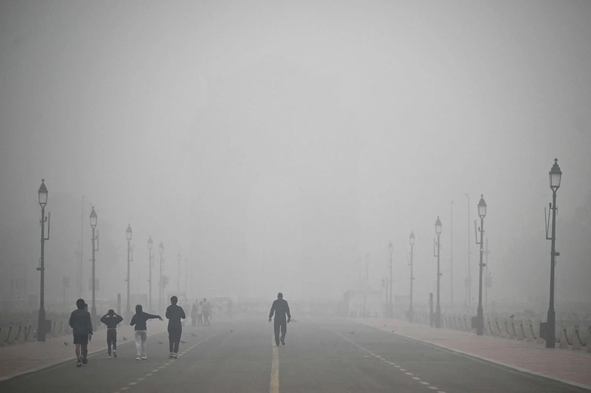 Pedestrians walk along the Kartavya Path engulfed in thick smog, near India Gate in New Delhi on November 18, 2024. (AFP)
