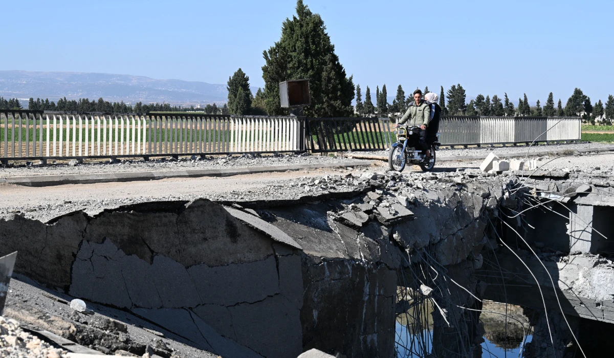 A couple cross on a motorcycle a bridge, damaged in an Israeli strike near the Syrian village of Tall al-Nabi Mando, in the countryside of Qusayr on October 28, 2024. (AFP)