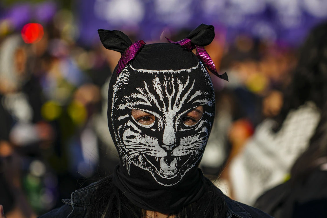 A woman wearing a mask performs during a march marking the International Day for the Elimination of Violence against Women in Santiago, Chile. (AP)
