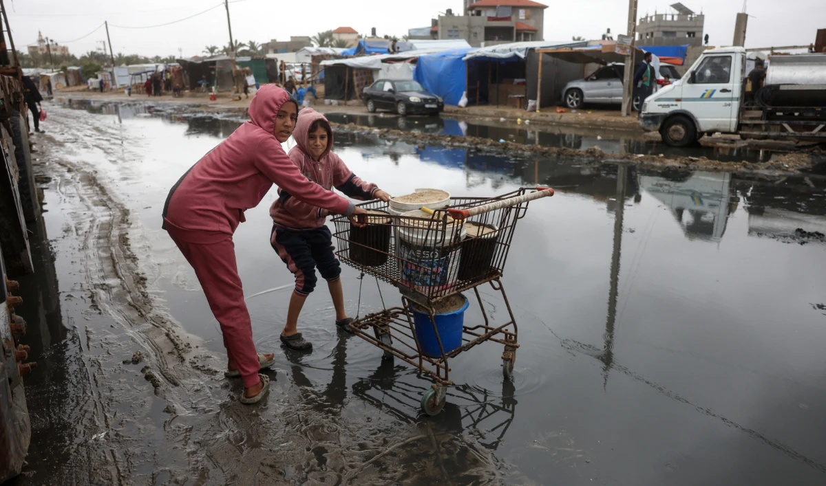Displaced Palestinian children transport sand from the nearby beach to be used for making sand bags for protecting tents from the rain, following heavy rainfall north of Deir El-Balah in the central Gaza Strip on November 24, 2024. (AFP)