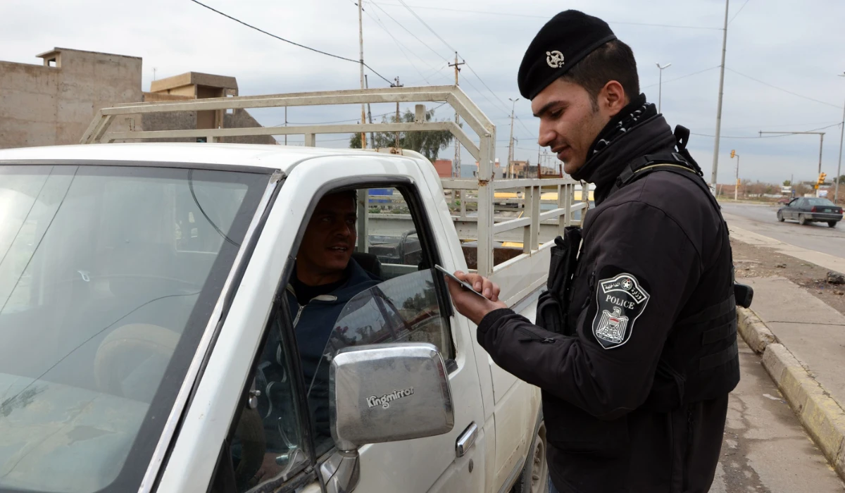 An Iraqi policeman checks the ID of a driver at a checkpoint in Mosul on February 22, 2018. (AFP)