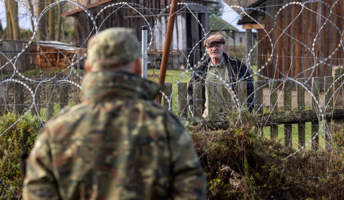 Michal Bura, a spokesman for the Podlasie region border guards, talks with a local resident through "concertina" barbed-wire fence in Minkowce village, Podlasie region, eastern Poland on November 15, 2024. (AFP)