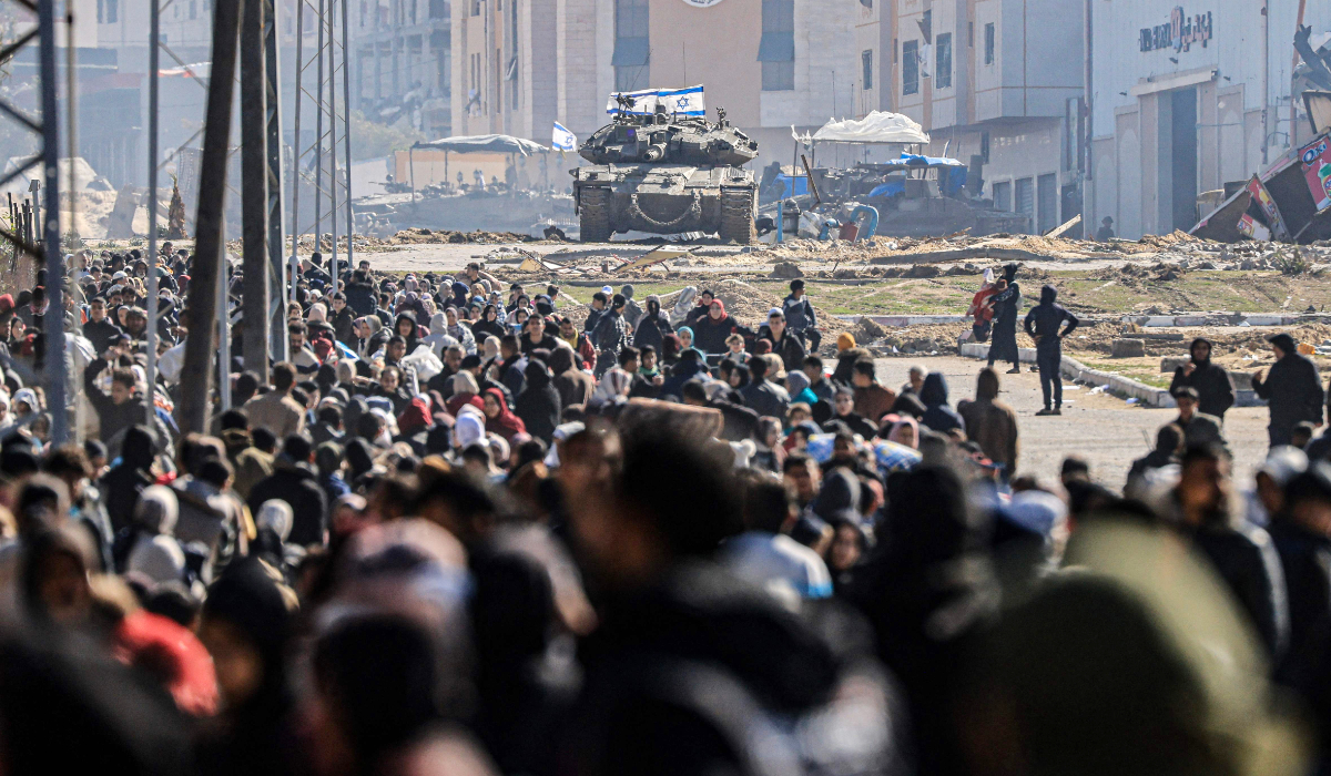 An Israeli tank and other military vehicles guard a position as Palestinians flee Khan Yunis, in the southern Gaza Strip, on January 26, 2024, amid ongoing battles between Israel and the Palestinian militant group Hamas. (AFP)