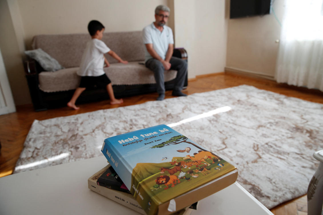 Nevzat Yesilbagdan and his seven-year-old son Muhammed Mesrur, with an anthology of children's stories in Kurdish in the foreground, are seen during an interview with Reuters at their home in Istanbul, Turkey, September 4, 2024. (Reuters)
