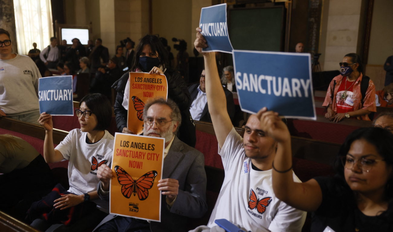 People in the audience hold up signs in support of immigrants as the Los Angeles City Council considers a "sanctuary city" ordinance during a meeting at City Hall in Los Angeles, California, on November 19, 2024. (AFP/File)