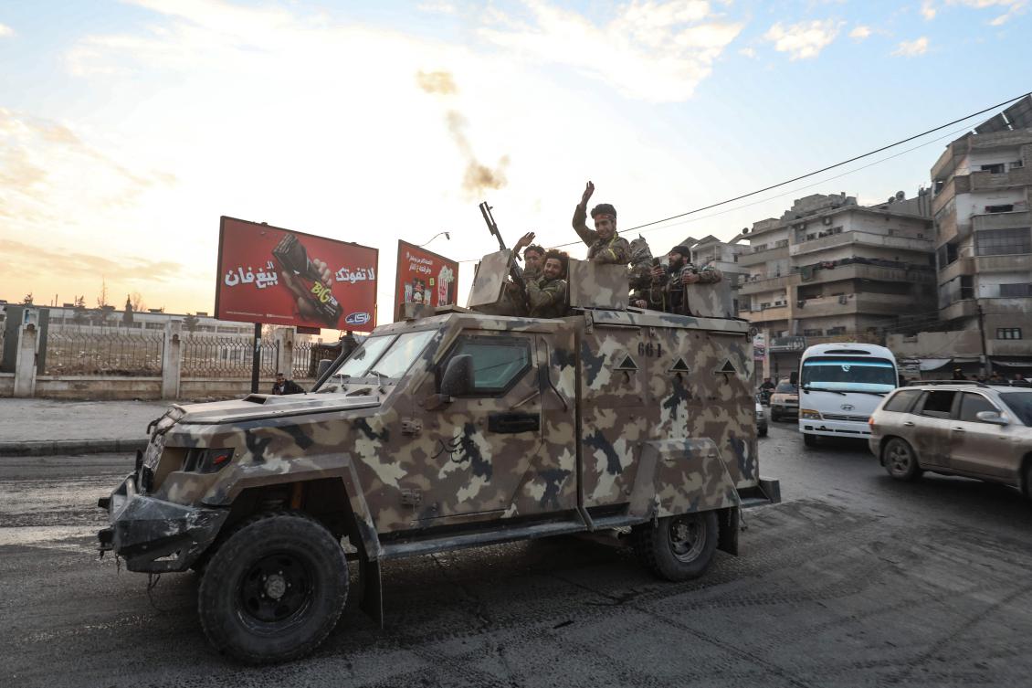 Syrian anti government fighters cheer as they ride a military vehicle through the streets of the west-central city of Hama on Dec. 5, 2024. (AFP)