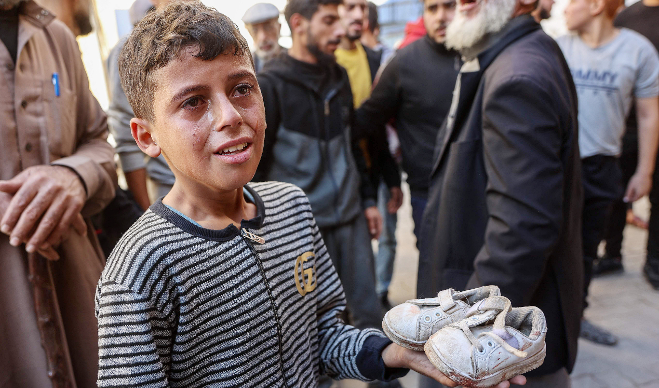 A boy holds the shoes of a toddler who was killed from shrapnel following an Israeli strike at Al-Ahli Arab Hospital in Gaza City. (AFP)