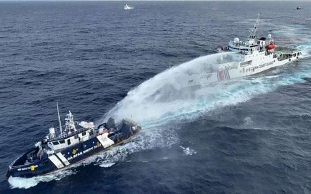 A China Coast Guard ship, right, deploys water cannon at the Philippine Bureau of Fisheries and Aquatic Resources vessel BRP Datu Pagbuaya near Scarborough Shoal in disputed waters of the South China Sea on Dec. 4, 2024. (NTF-WPS/AFP)