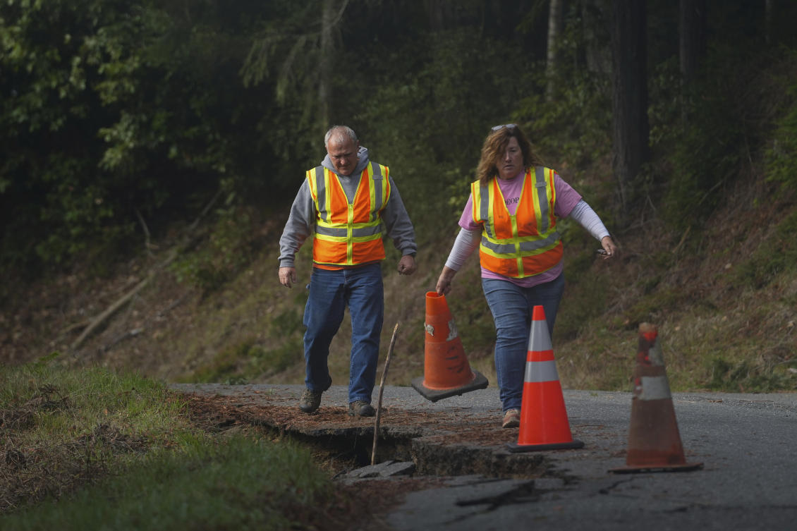 California maintenance workers prepare to fill cracks with dirt on a road damaged by a Thursday's earthquake. (AP)