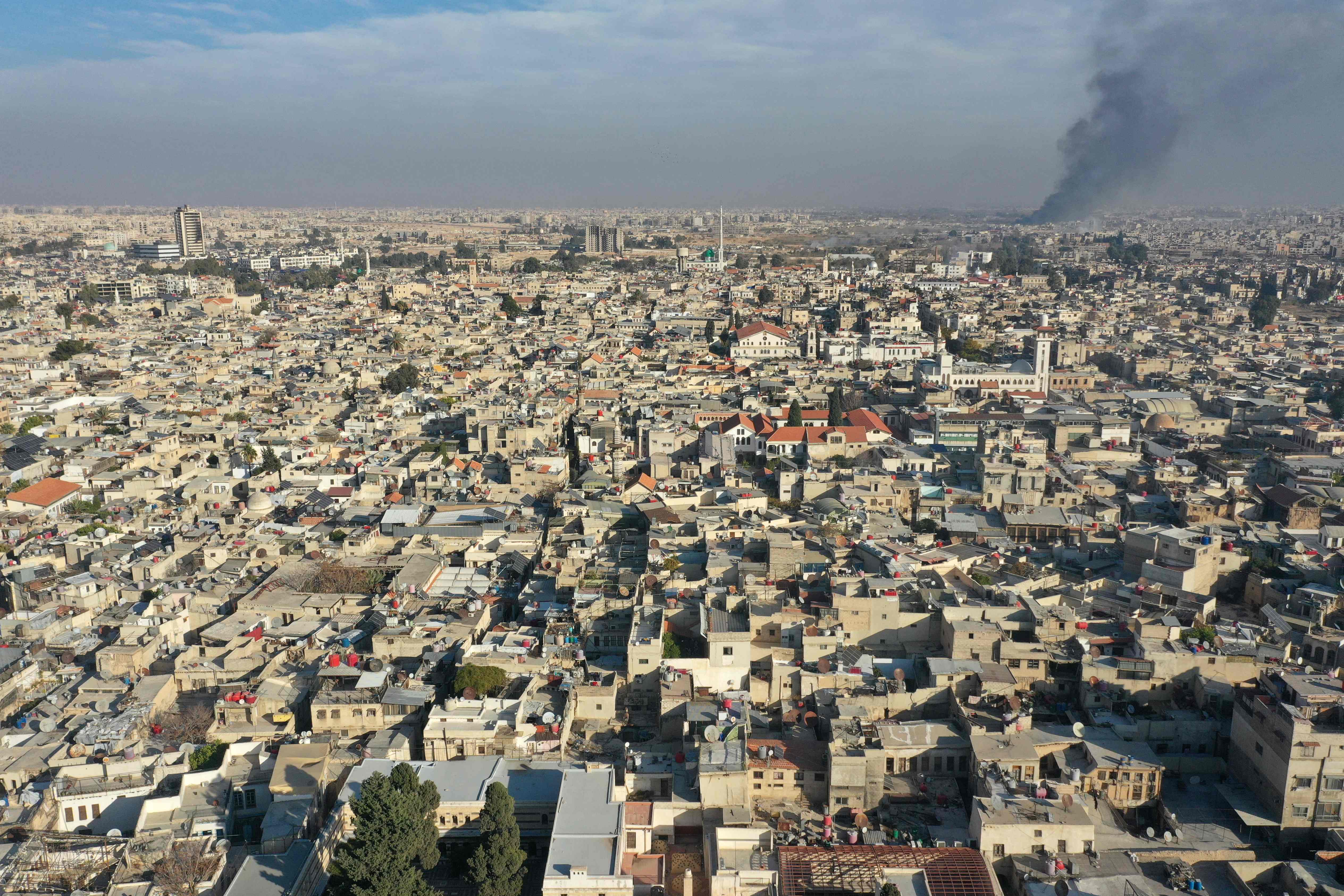Aerial photo shows Damascus on Dec. 8, 2024, with smoke billowing in the background after militants declared that they have taken the Syrian capital in a lightning offensive, sending President Bashar Assad fleeing and ending five decades of rule in Syria. (AFP)