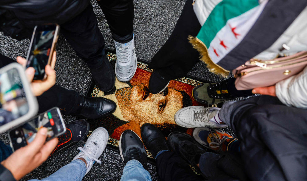 Demonstrators trample a carpet with a design showing President Bashar Al-Assad during a protest. (AFP)