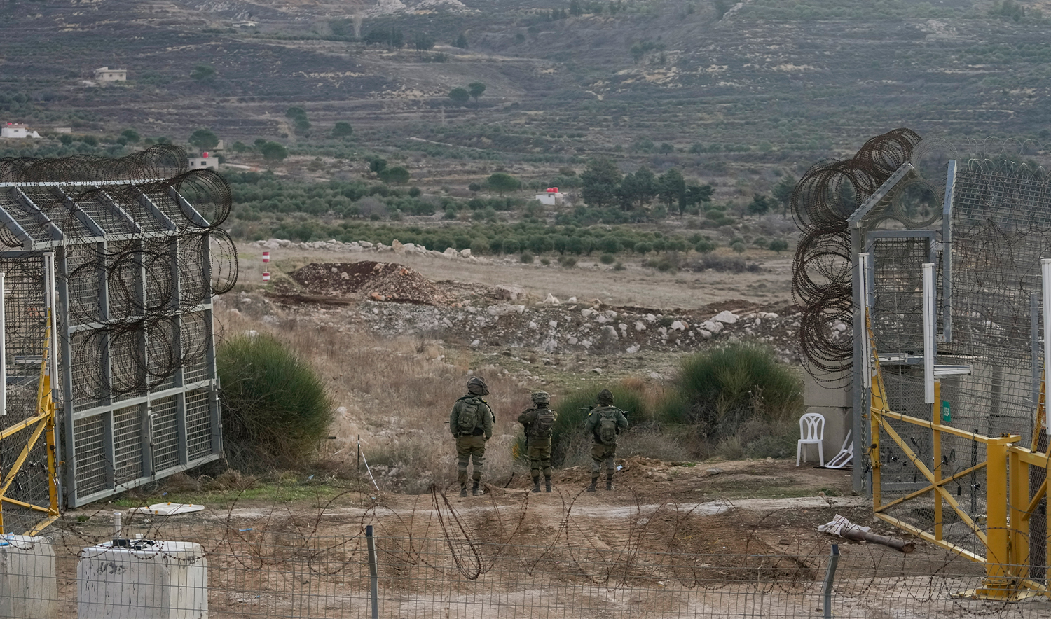 Israeli soldiers stand guard on a security fence gate near the so-called Alpha Line that separates the Israeli-occupied Golan Heights from Syria, in the town of Majdal Shams, on December 9, 2024. (AP)