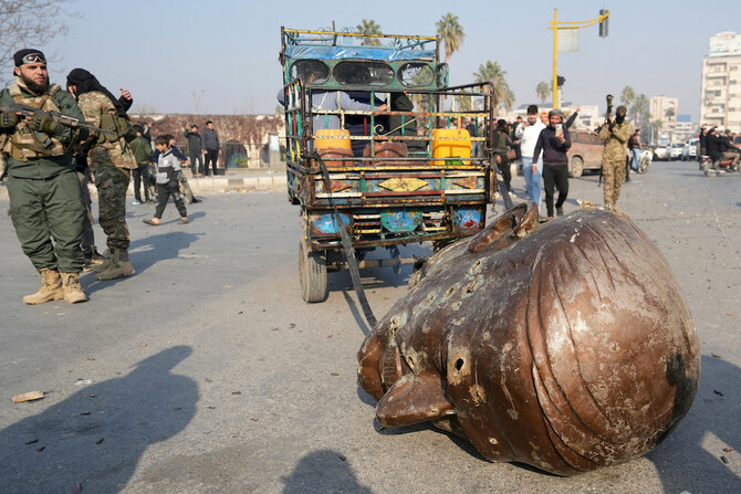 A truck pulls the head from the toppled statue of late Syrian president Hafez Al-Assad through the streets of the captured Syrian city of Hama. (AFP)