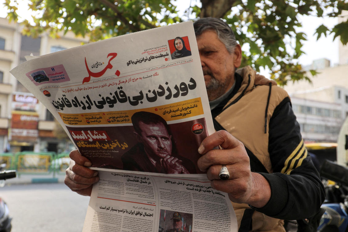 FILE PHOTO: An Iranian man reads a newspaper with a picture of Syrian President Bashar al-Assad in Tehran, Iran December 8, 2024. (Majid Asgaripour/West Asia News Agency via Reuters)