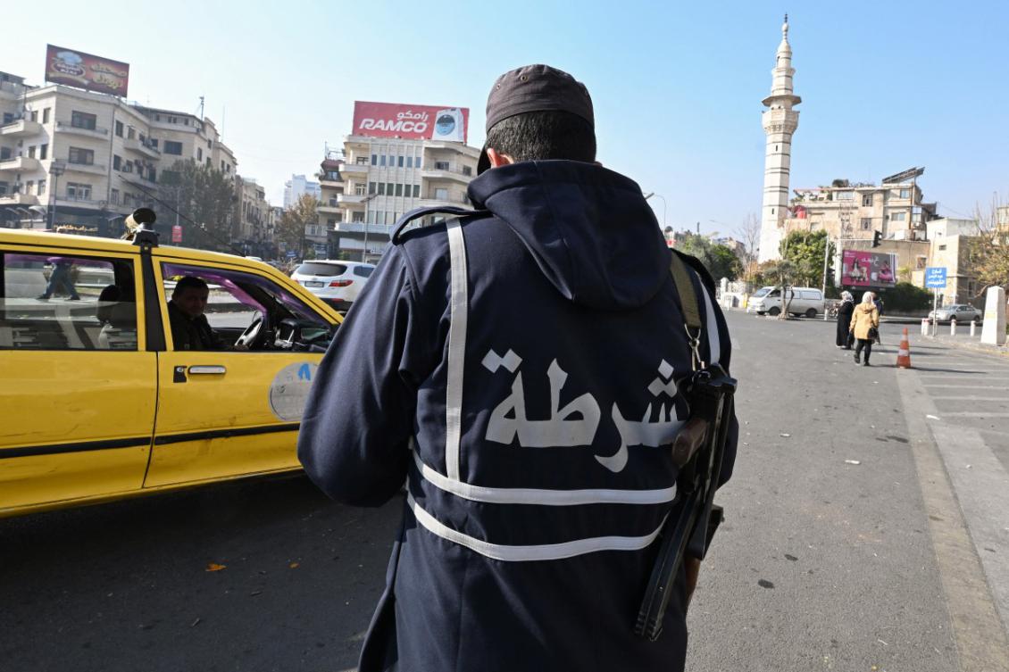 A policeman from the group Hayat Tahrir al-Sham (HTS)'s so-called "Salvation Government", stands guard in front of Syria's Central Bank in Damascus, on December 9, 2024, after the group took over the city and ousted Syrian president Bashar al-Assad. (AFP)