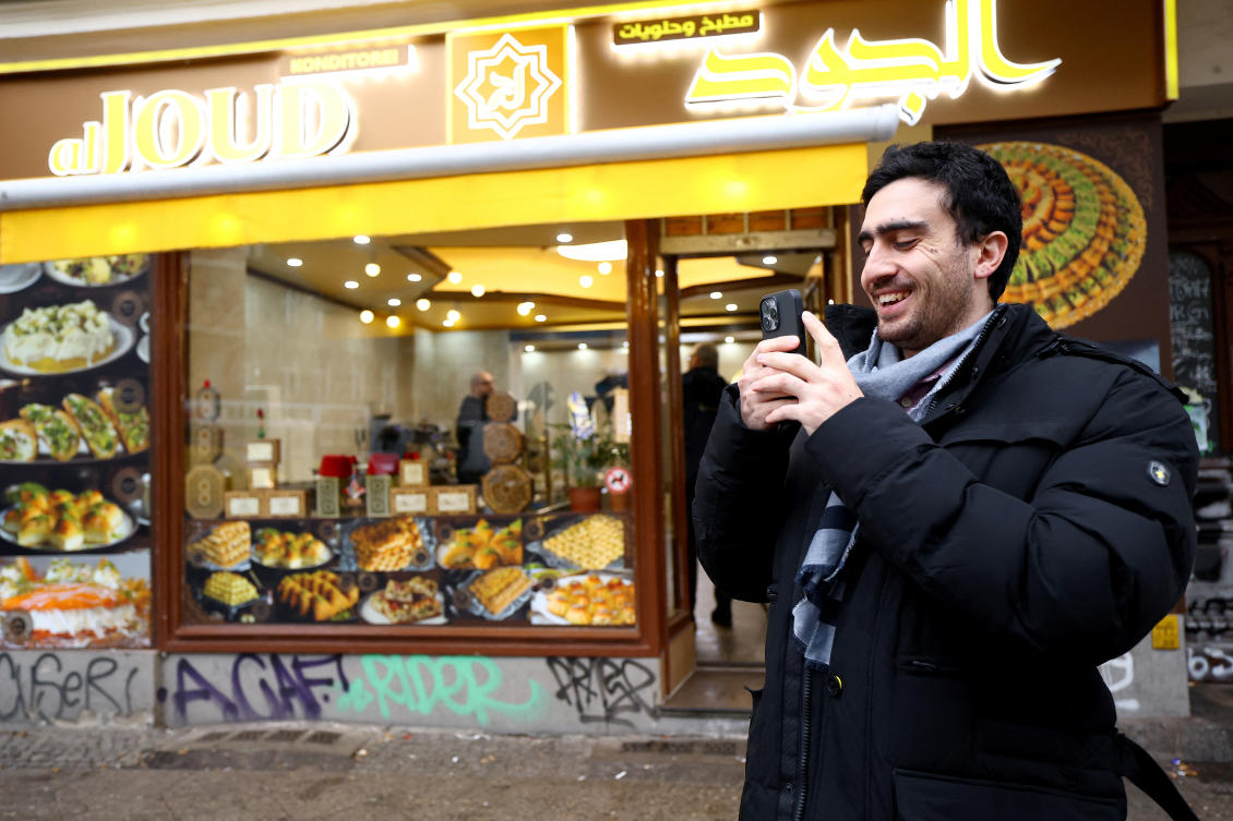 Syrian refugee Anas Modamani records a video with his phone in front of Aljoud bakery in Neukolln district in Berlin, Germany December 9, 2024. (Reuters)
