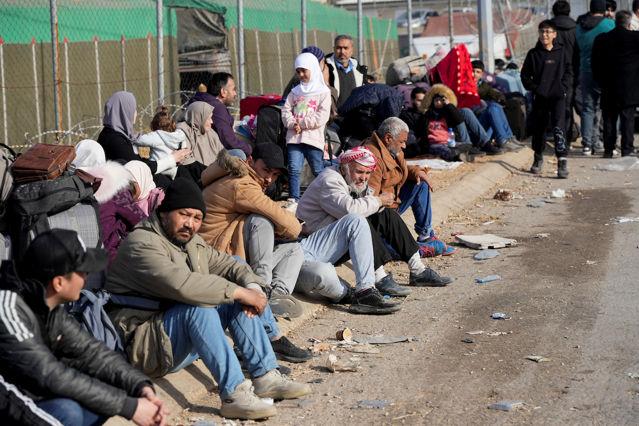 People sit as they wait to cross into Lebanon at the Masnaa border crossing between Lebanon and Syria, on December 9, 2024. (Reuters)