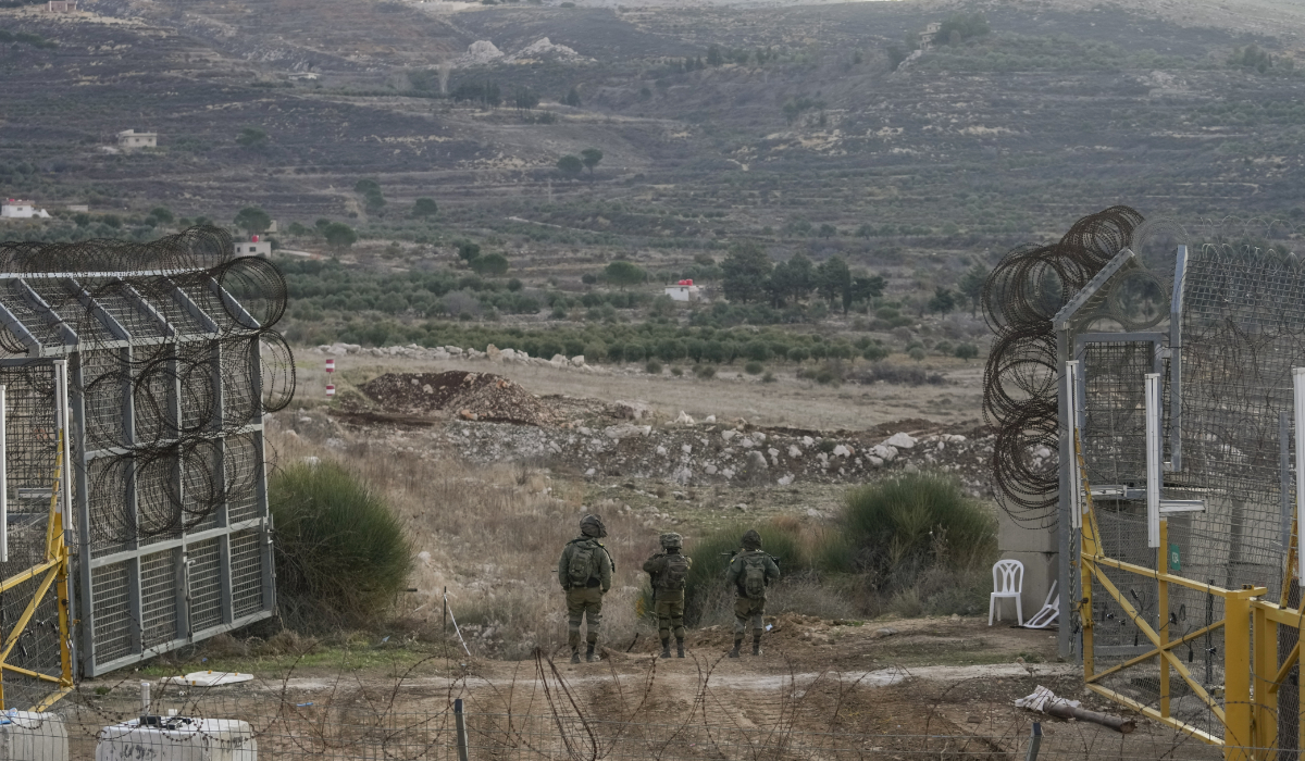 Israeli soldiers stand guard on a security fence gate near the so-called Alpha Line that separates the Israeli-occupied Golan Heights from Syria, in the town of Majdal Shams, Monday, Dec. 9, 2024. (AP)