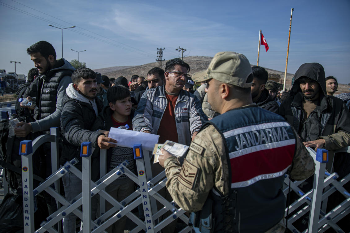 Syrians talk to a Turkish gendarme officer as they wait to cross into Syria from Turkey at the Cilvegozu border gate, near the town of Antakya, southern Turkey, Monday, Dec. 9, 2024. (AP)