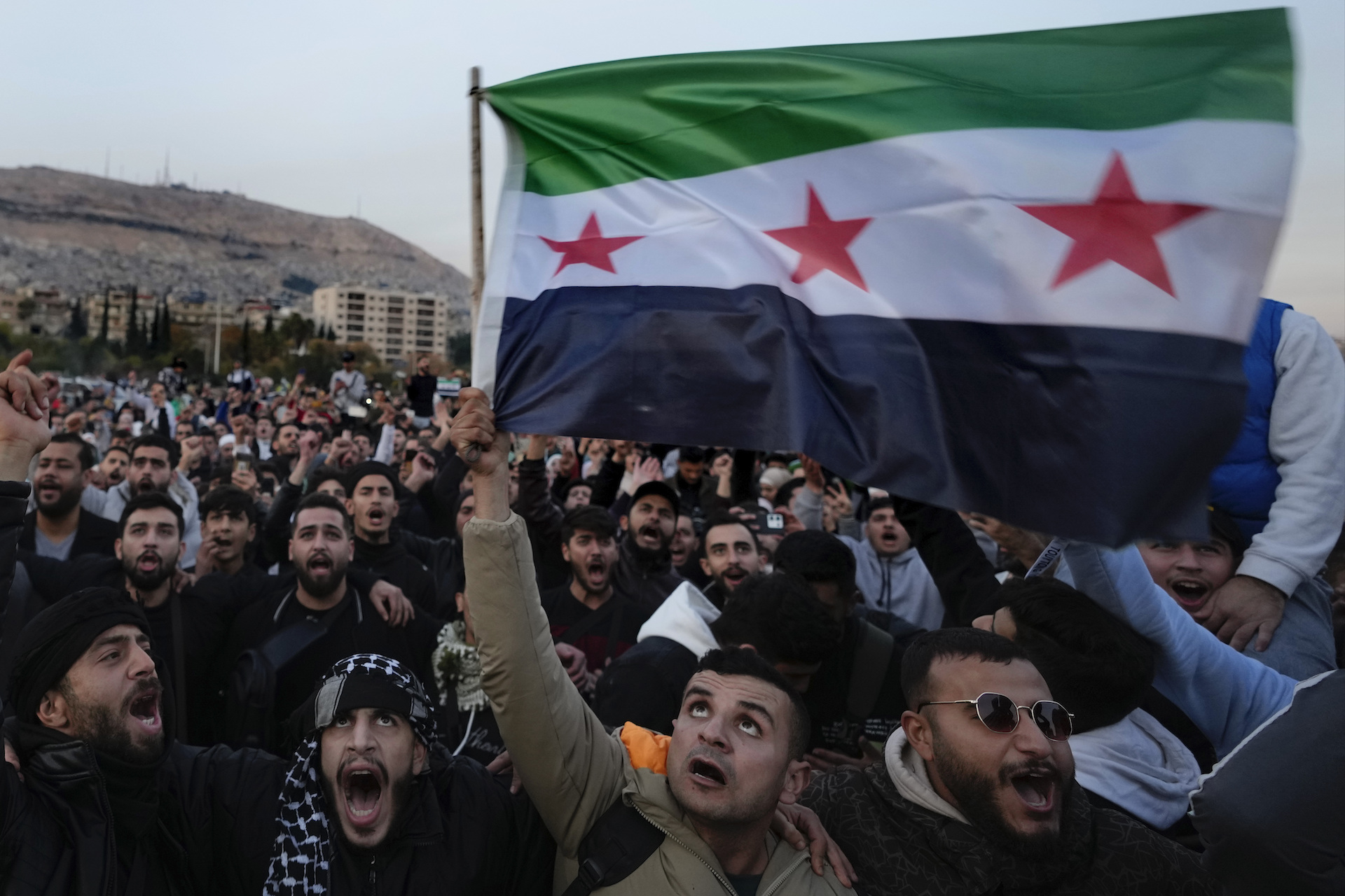 Syrian citizens wave the revolutionary flag and shout slogans, as they celebrate during the second day of the take over of the city by militants in Damascus, Syria, Monday, Dec. 9, 2024. (AP)