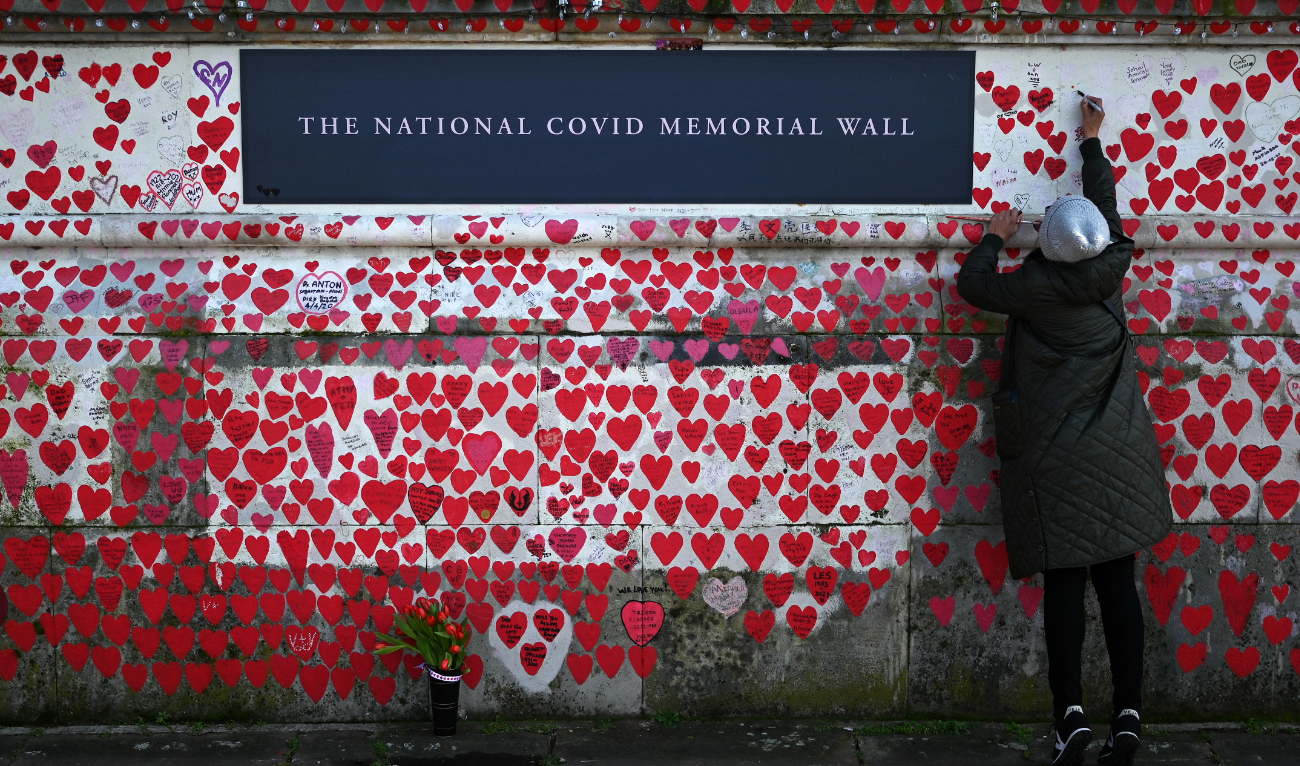 A person writes on The National Covid Memorial Wall, dedicated to those who lost their lives to Covid-19, on the embankment on the south side of the River Thames in London on March 3, 2024. (AFP/File)