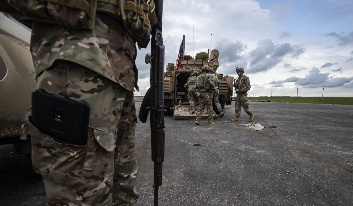 A member of the Syrian Democratic Forces (SDF) (L) and US soldiers are pictured near an armoured military vehicles are pictured on the outskirts of Rumaylan in Syria's northeastern Hasakeh province, bordering Turkey, on March 27, 2023. (AFP)
