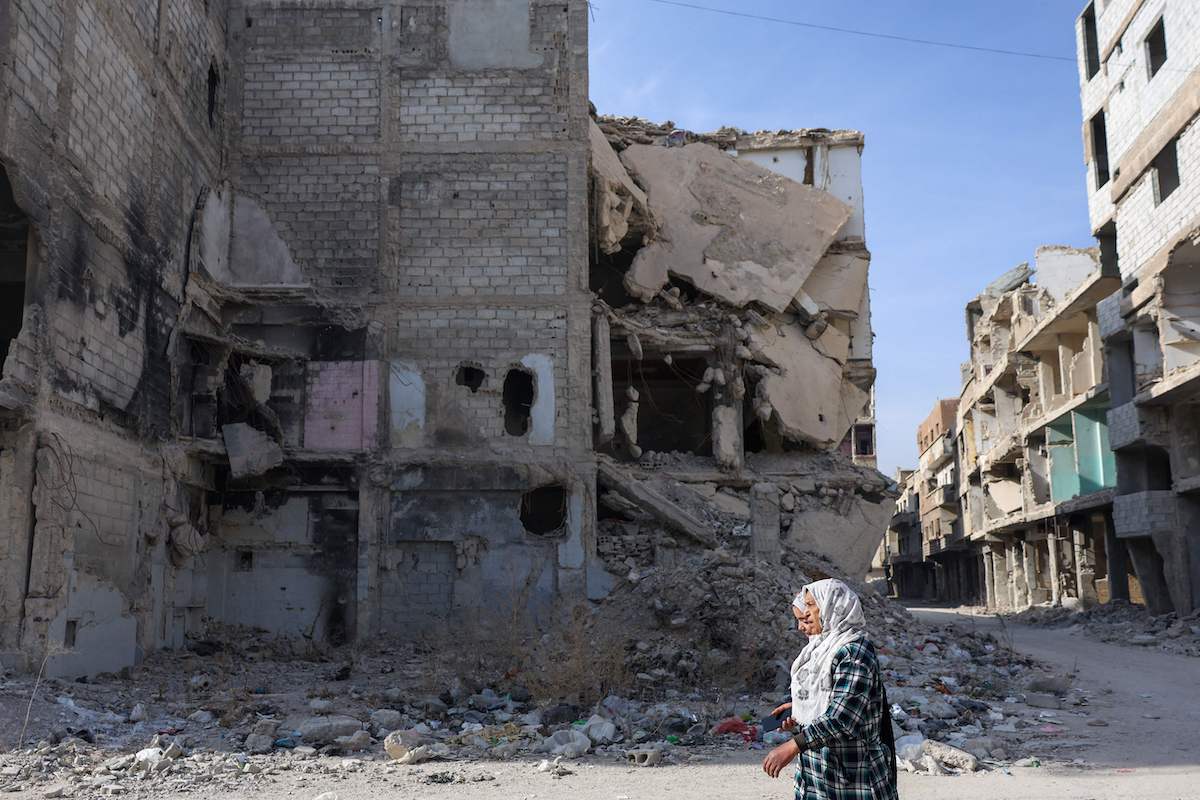 Two women walk past a destroyed building at the Yarmouk refugee camp in southern Damascus. (AFP)
