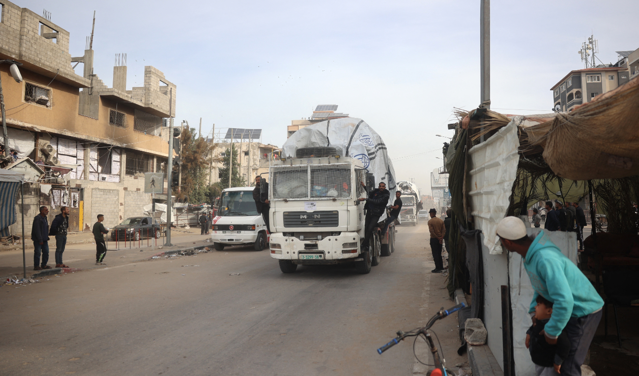 Men stand guard on the side of the truck carrying humanitarian aid as it drives on the main Salah al-Din road in the Nuseirat refugee Camp in the central Gaza Strip on December 7, 2024. (AFP/File)