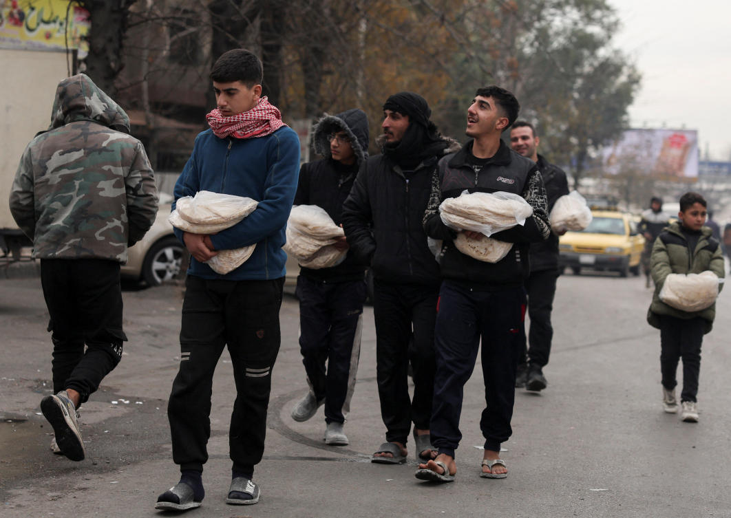 People walk with food in plastic bags, after rebels seized the capital and ousted Syria's Bashar Assad, in Damascus on Thursday. (Reuters)