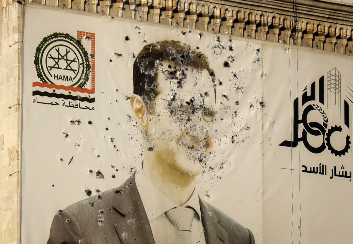 An image of ousted Syrian President Bashar Assad covers the facade of a provincial government office in Hama. UK politicians are debating whether the West should have acted against Assad in 2013. (AP)