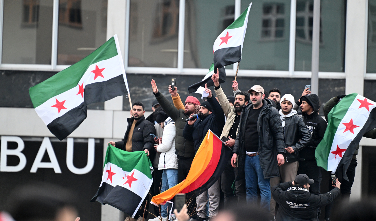 Members of the Syrian community hols flags of Syria and Germany as they rally on December 8, 2024 in Berlin, Germany, to celebrate the end of Syrian dictator Bashar Assad's rule. (AFP/File)