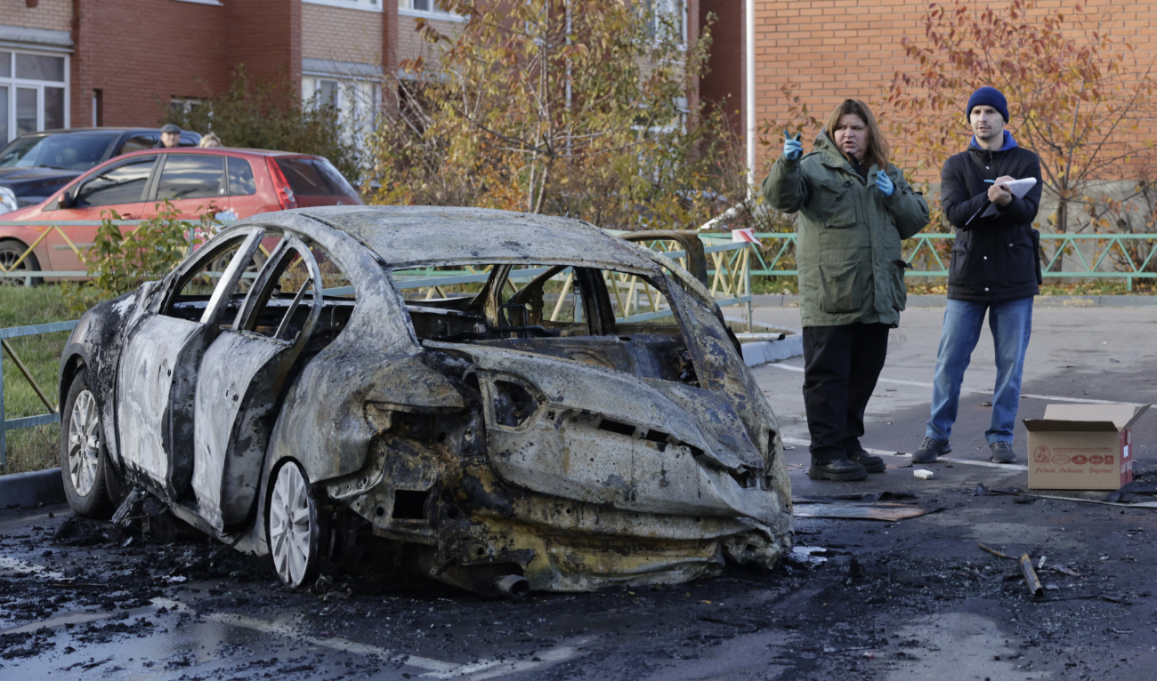 Russian law enforcement officers inspect a burnt-out car in the courtyard of residential buildings following a drone attack in the village of Sofyino, Moscow region, on November 10, 2024. (AFP/File)