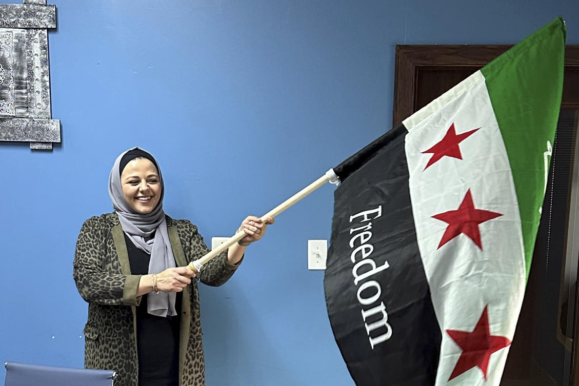 Rama Alhoussaini holds a Syrian flag in her Dearborn Heights, Mich., office, Tuesday, Dec. 10, 2024. (AP)
