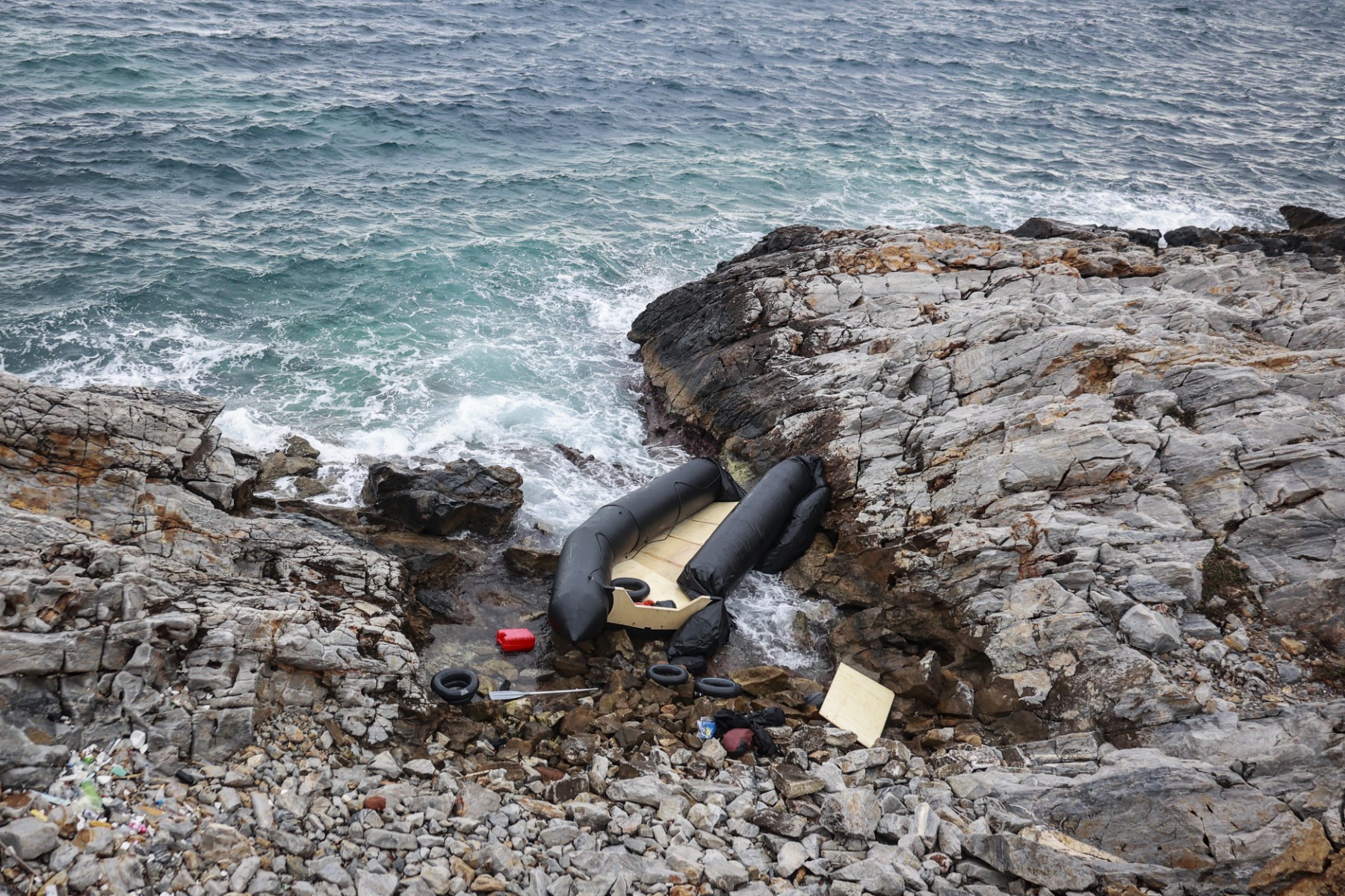 File photo A rubber boat, believed to be used by migrants, lies destroyed on the rocky shoreline, in Thermi on the Greek island of Lesbos on February 7, 2023.(AFP)