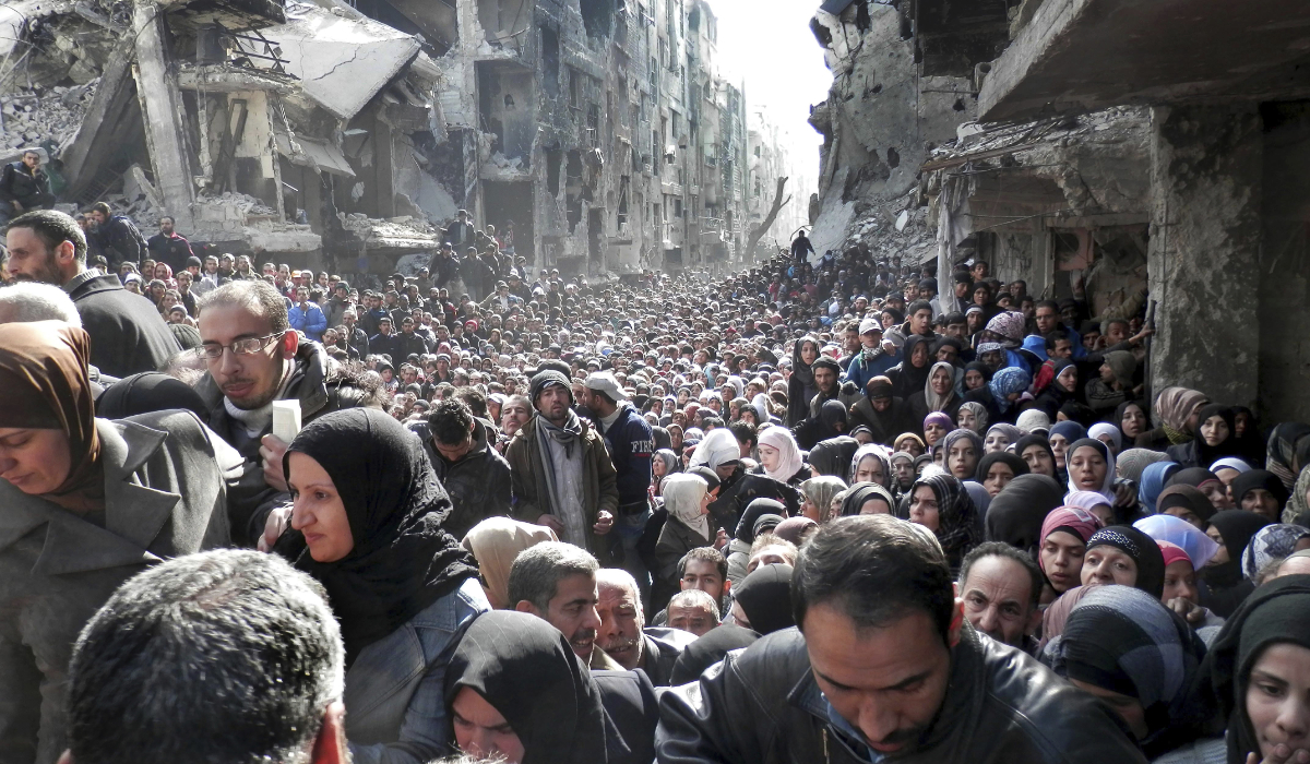 In this Jan. 31, 2014 file photo released by the United Nations Relief and Works Agency for Palestine Refugees in the Near East (UNRWA), shows residents of the besieged Palestinian camp of Yarmouk, lining up to receive food supplies, in Damascus, Syria. (AP)