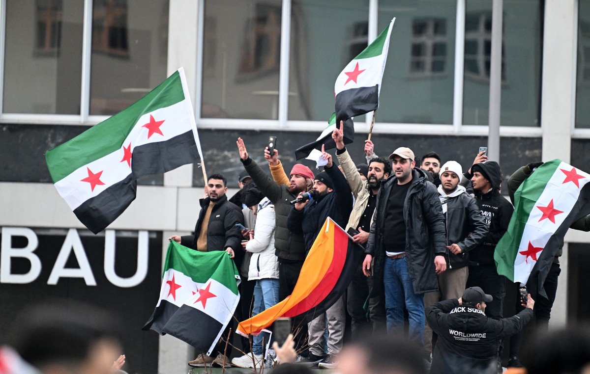 Members of the Syrian community hols flags of Syria and Germany as they rally on December 8, 2024 in Berlin, Germany, to celebrate the end of Syrian dictator Bashar al-Assad's rule after rebel fighters took control of the Syrian capital Damascus overnight. (AFP)