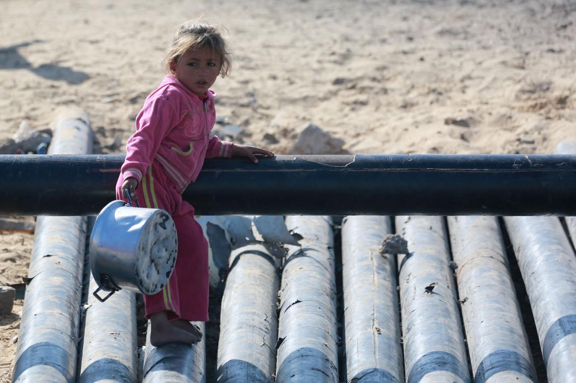 A Palestinian girl carries a pot as she waits for a food portion at a distribution centre south of Khan Yunis in the southern Gaza Strip on December 17, 2024. (AFP)